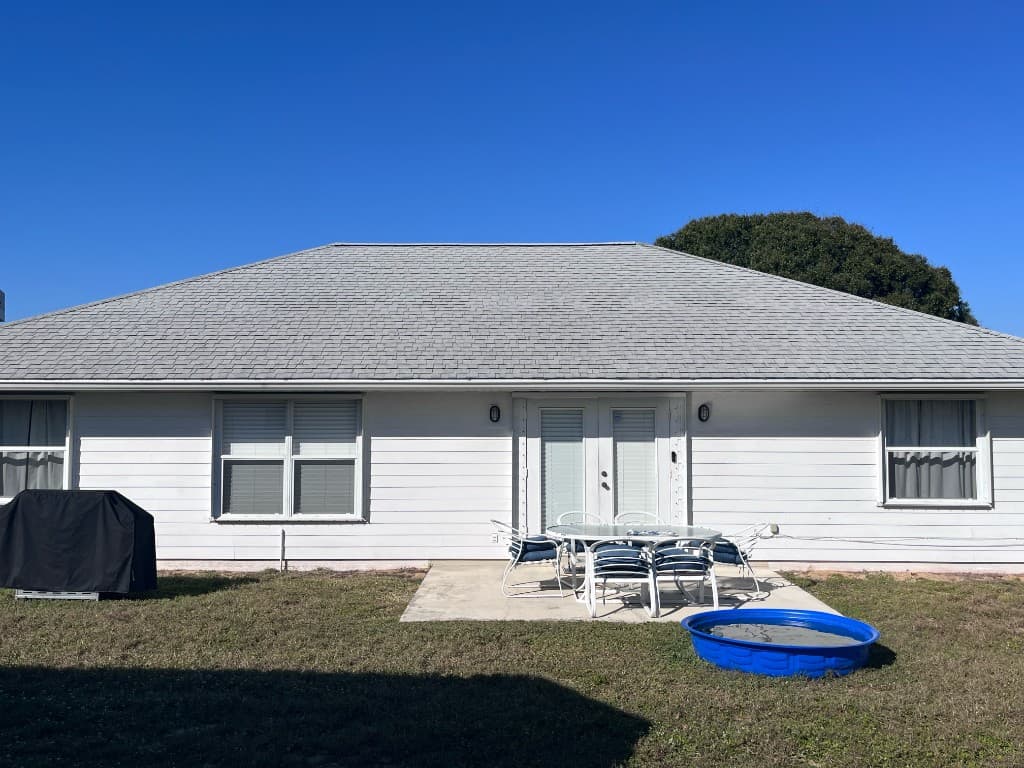 The front of a single-story house with a light gray shingle roof under a clear blue sky